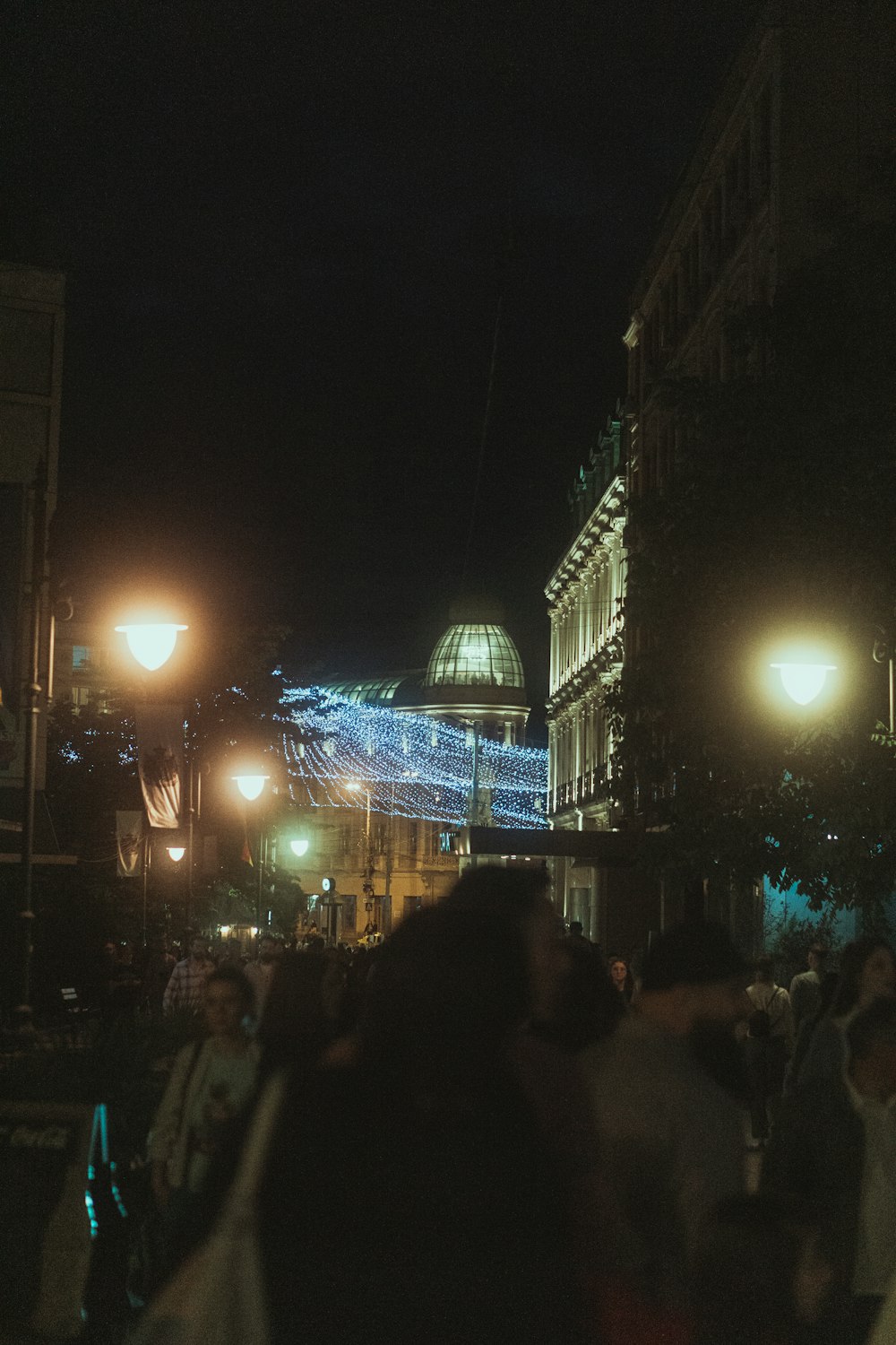 uma multidão de pessoas andando por uma rua à noite