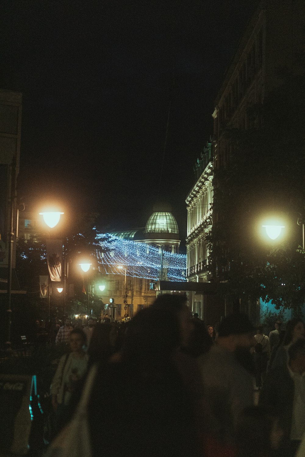 a crowd of people walking down a street at night