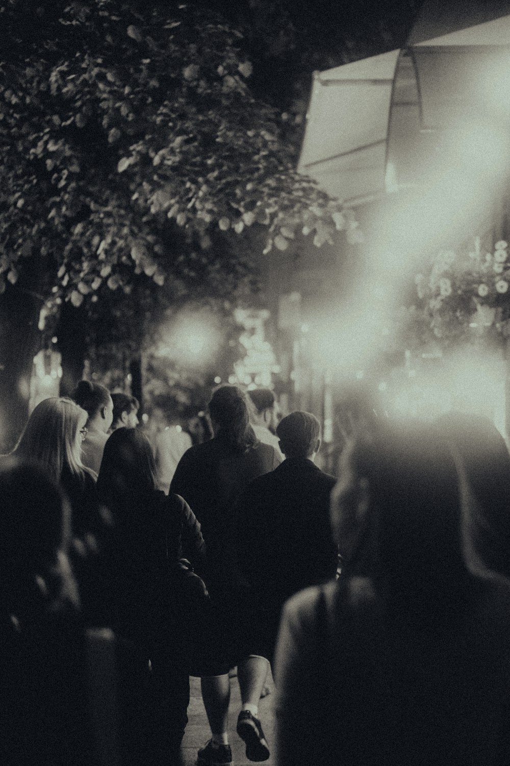 a group of people walking down a street at night