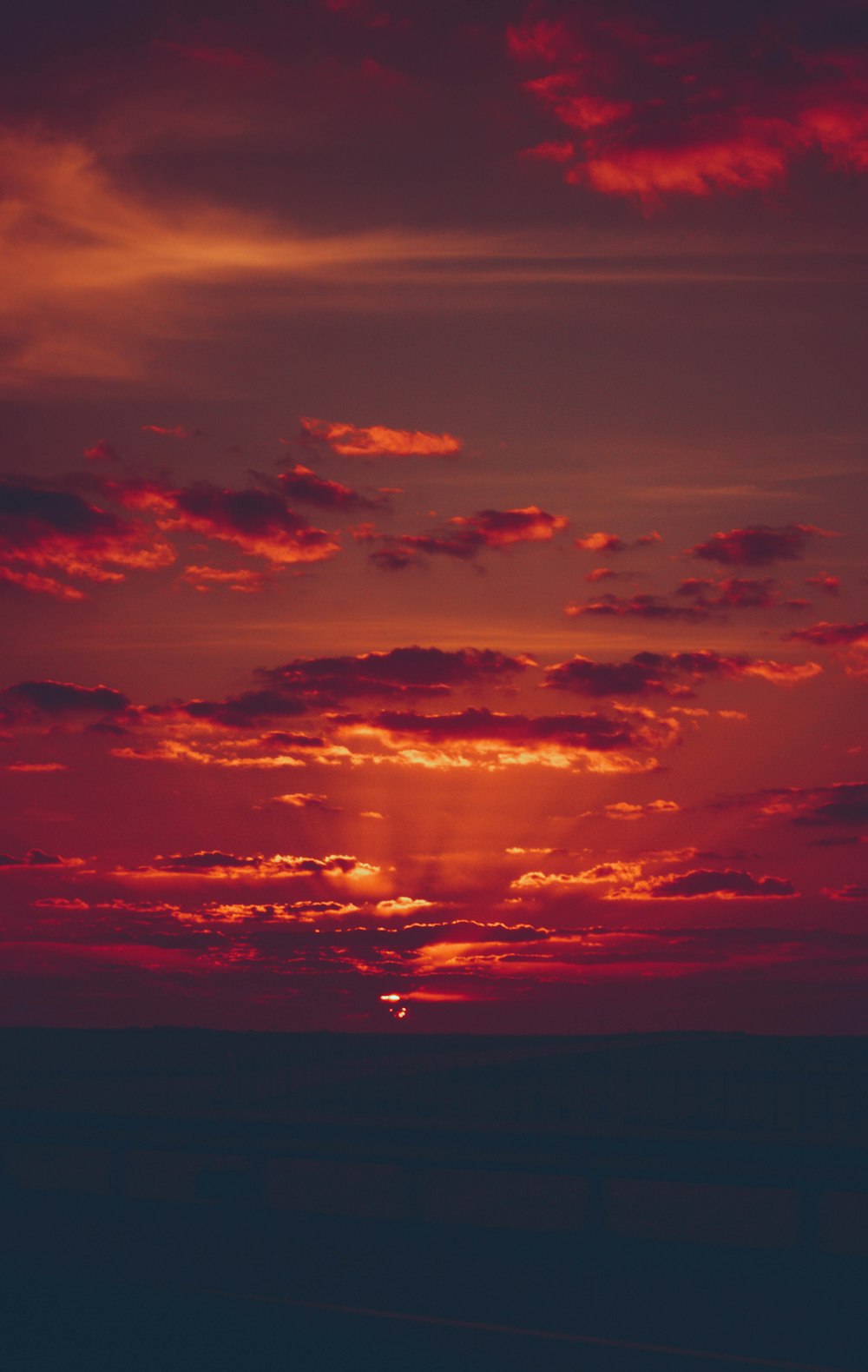 the sun is setting over the horizon of a body of water