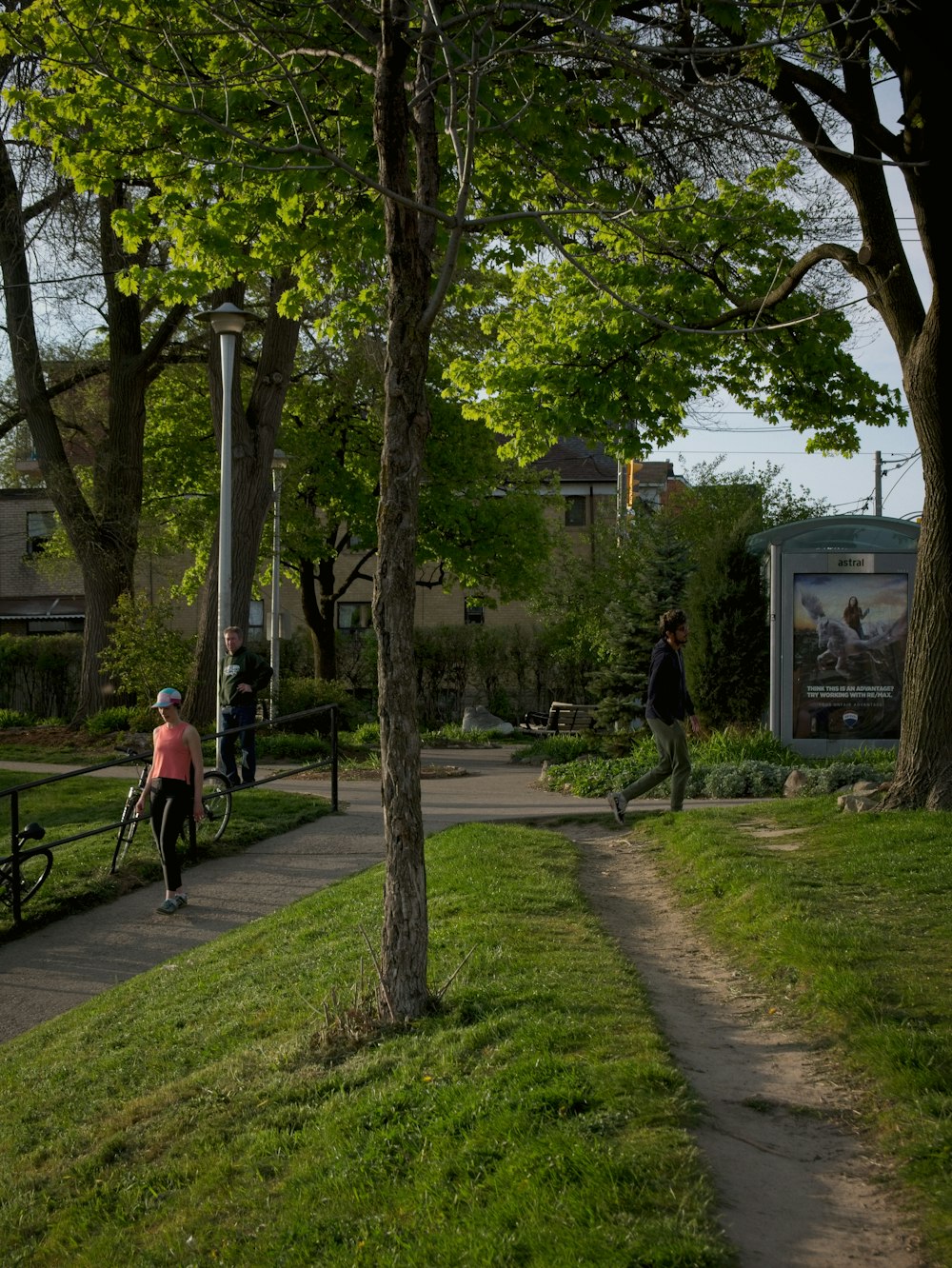 a woman riding a skateboard down a sidewalk next to a park