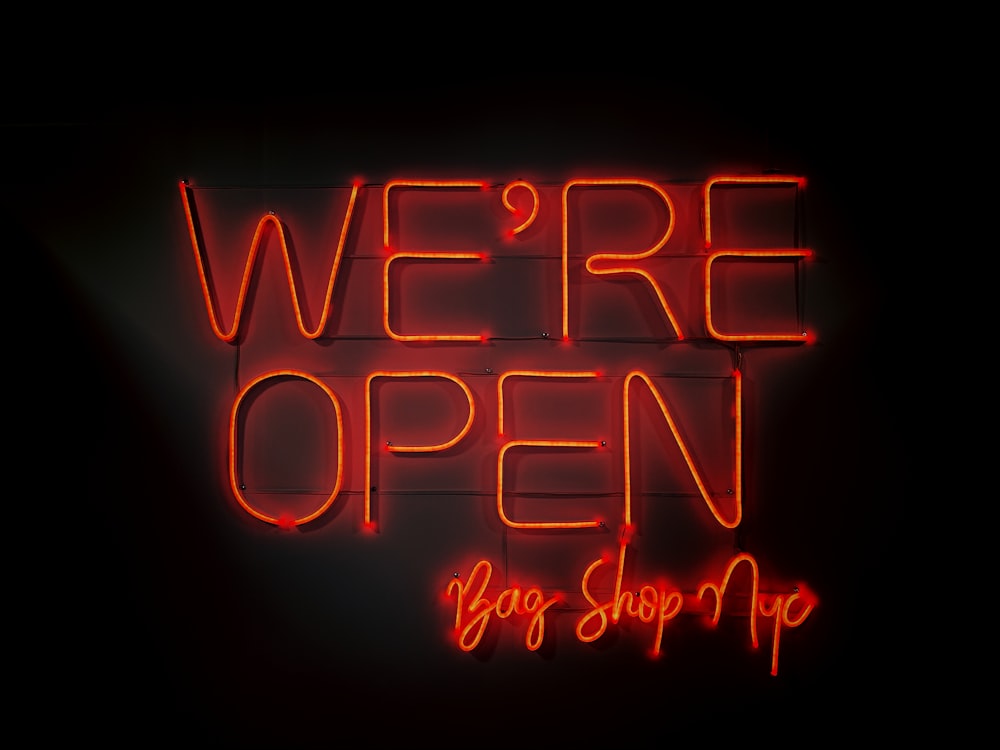 a neon sign that says we're open big shop up