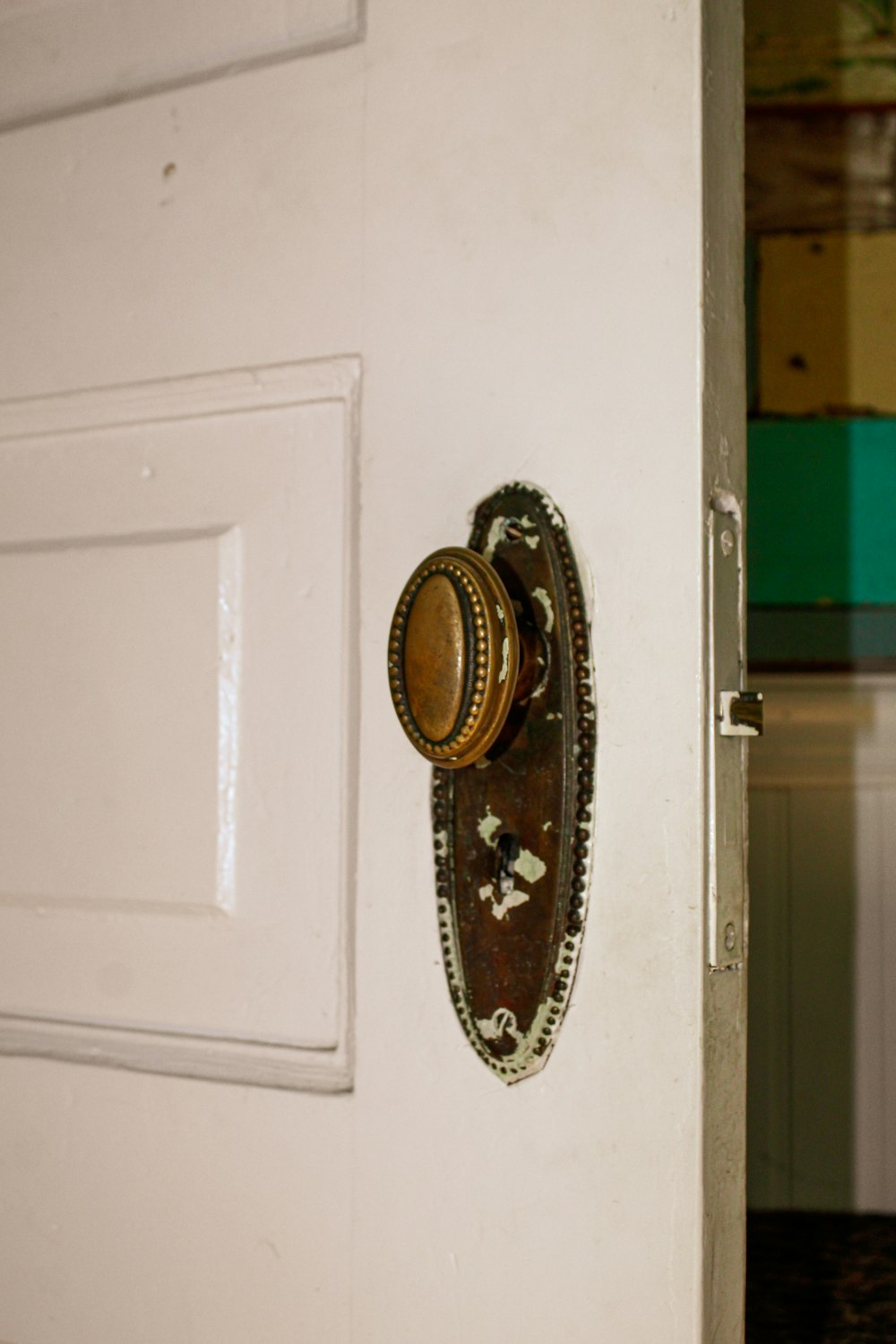 a door handle on a white door with a green wall in the background