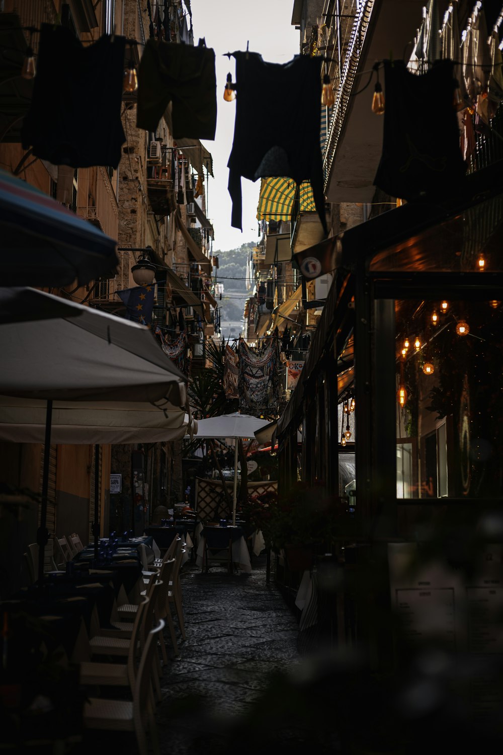 a narrow street with tables and umbrellas on both sides