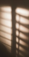 Abstract shadows cast by window blinds, evoking contemplation.