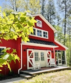 a red barn with a porch and a white rocking chair