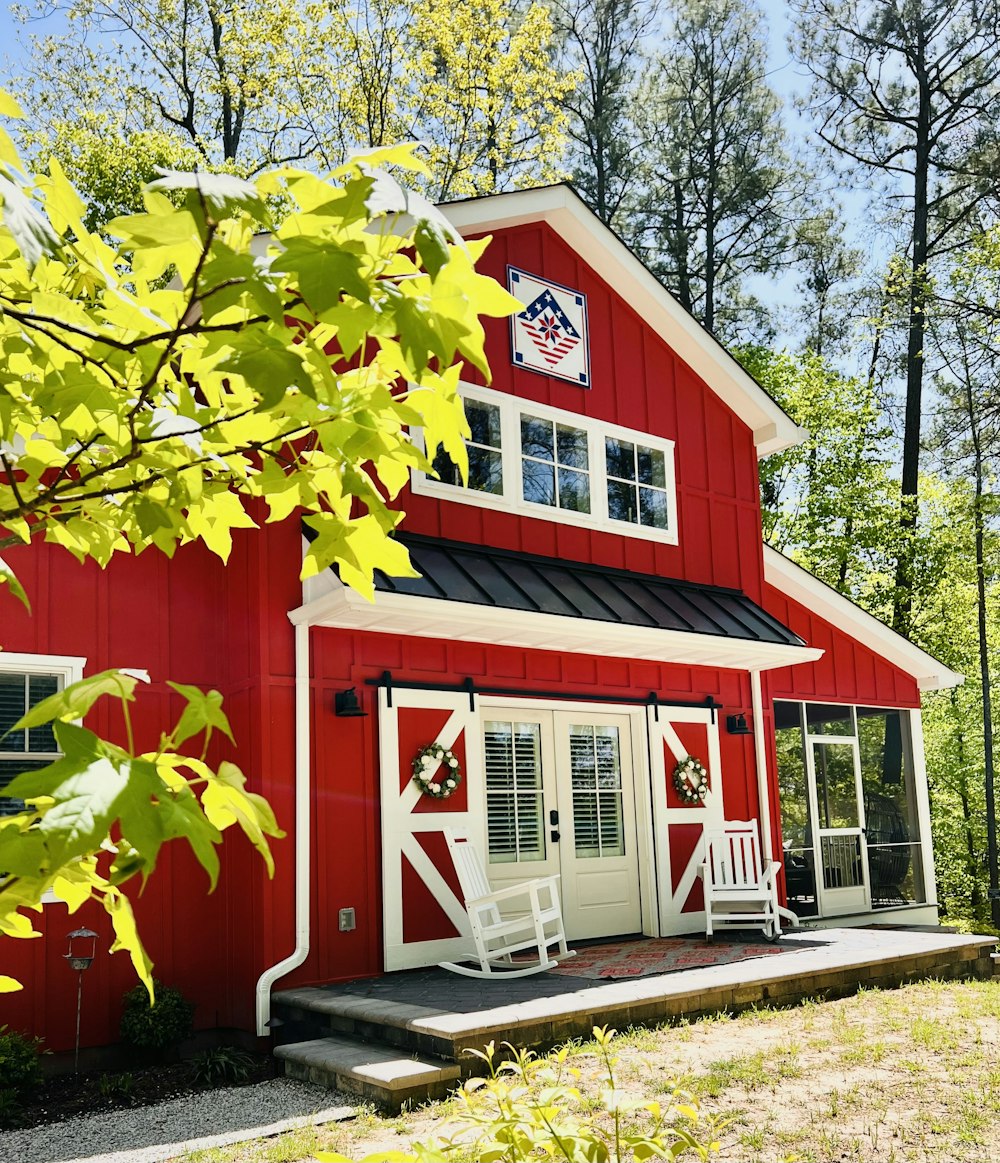 a red barn with a porch and a white rocking chair