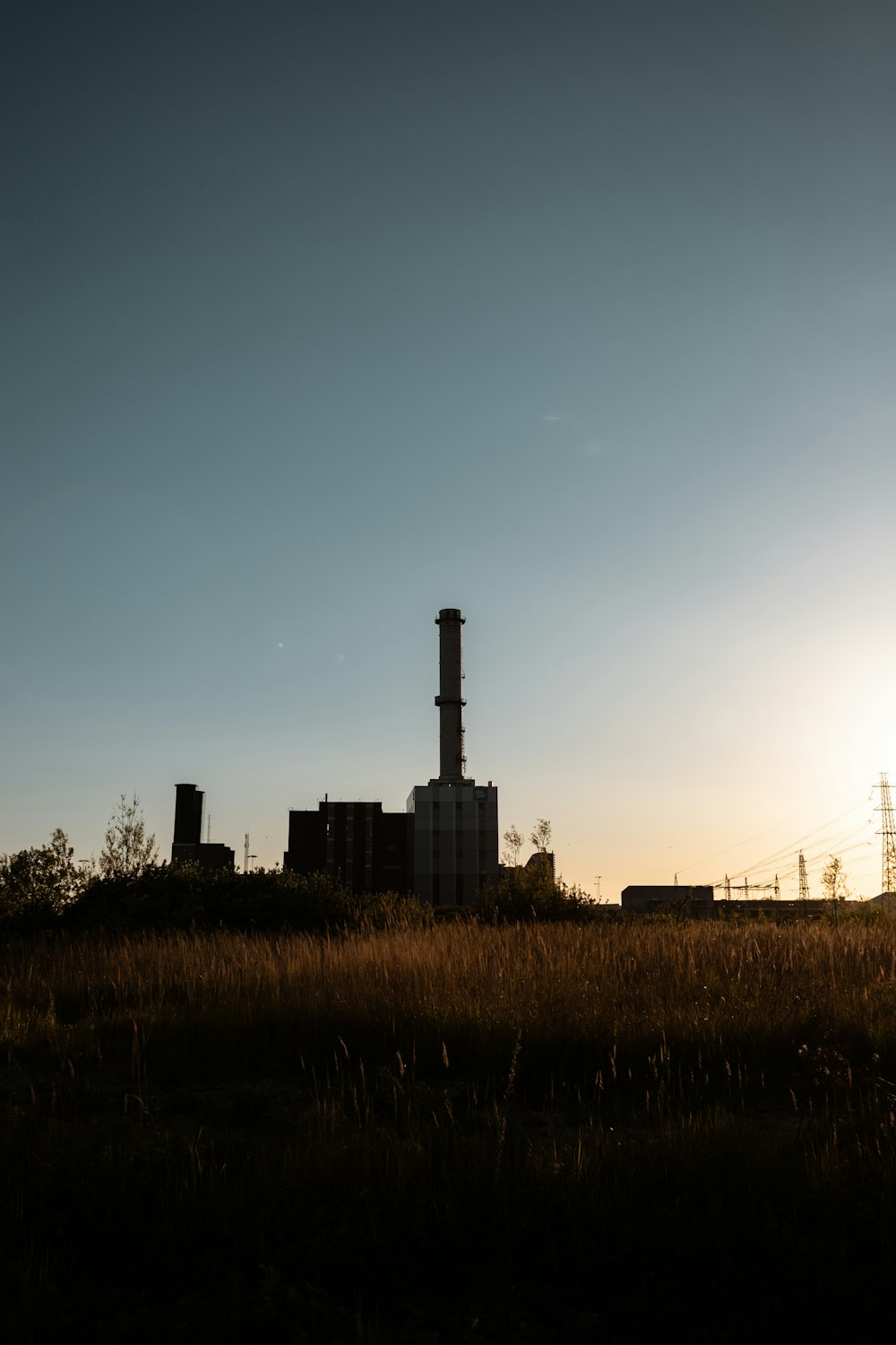 a factory in the distance with the sun in the background