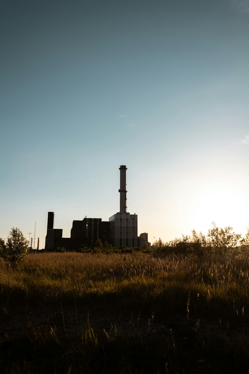 a factory in the distance with the sun in the background