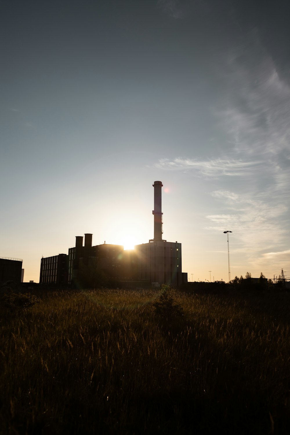 the sun is setting behind a factory building