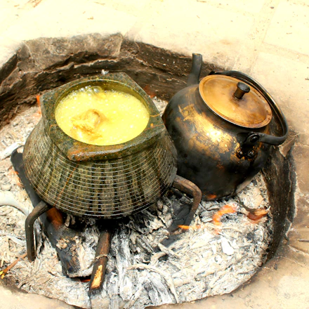 A bright solar cooker placed under direct sunlight with a pot inside, cooking food.