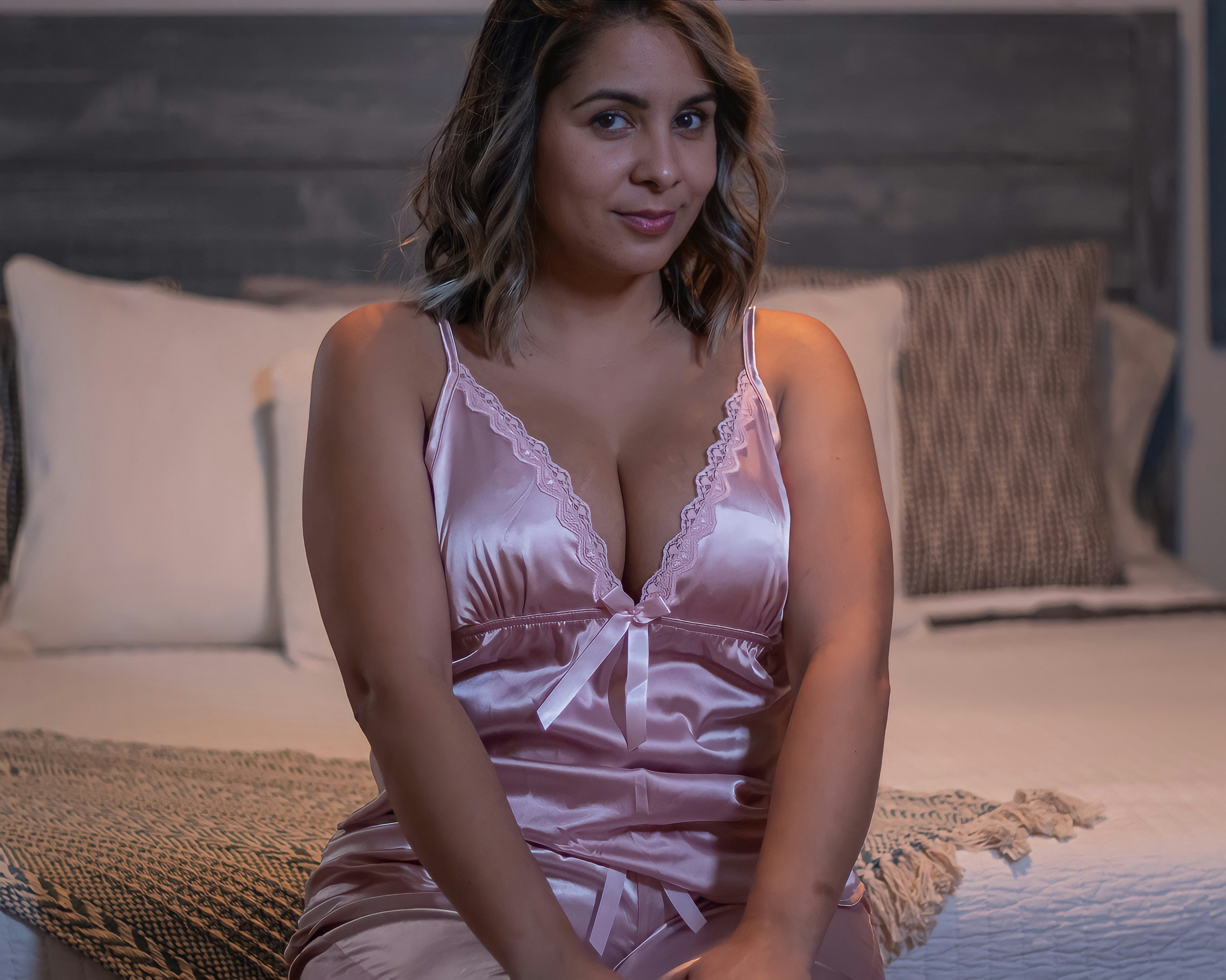 a woman sitting on a bed in a pink dress