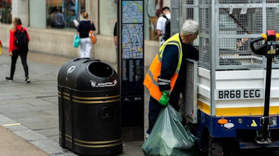 a man standing next to a trash can on the side of a road