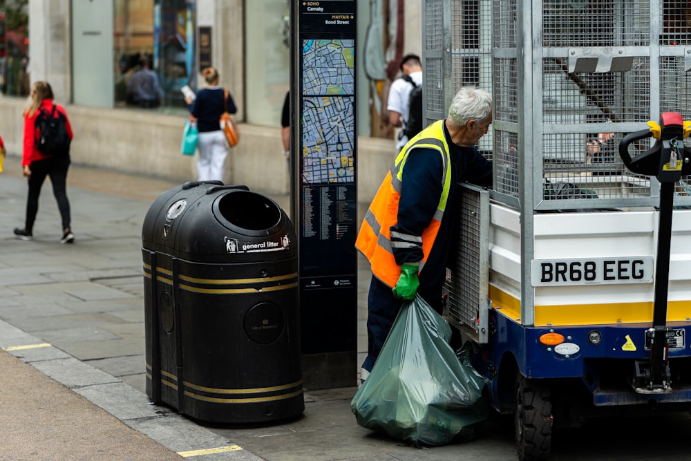 a man standing next to a trash can on the side of a road