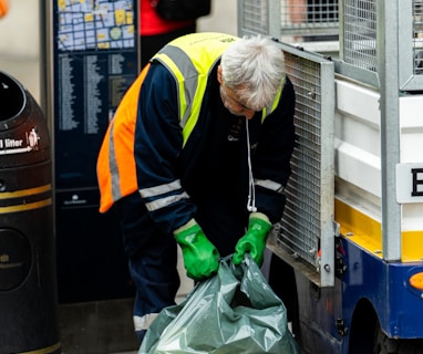 a man in a yellow safety vest and green gloves unloads a garbage bag