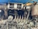 A detailed view of an engine part with various metallic components, including pipes, bolts, and connectors. The machinery appears old and worn, with visible rust and signs of usage. Several interconnected parts are assembled in a complex arrangement, suggesting industrial or automotive use.