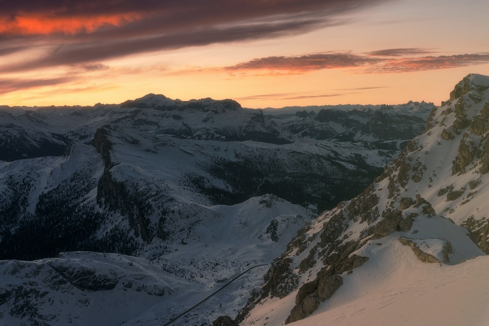 una vista di una montagna innevata con un tramonto sullo sfondo