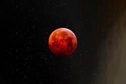 a red moon is seen in the night sky