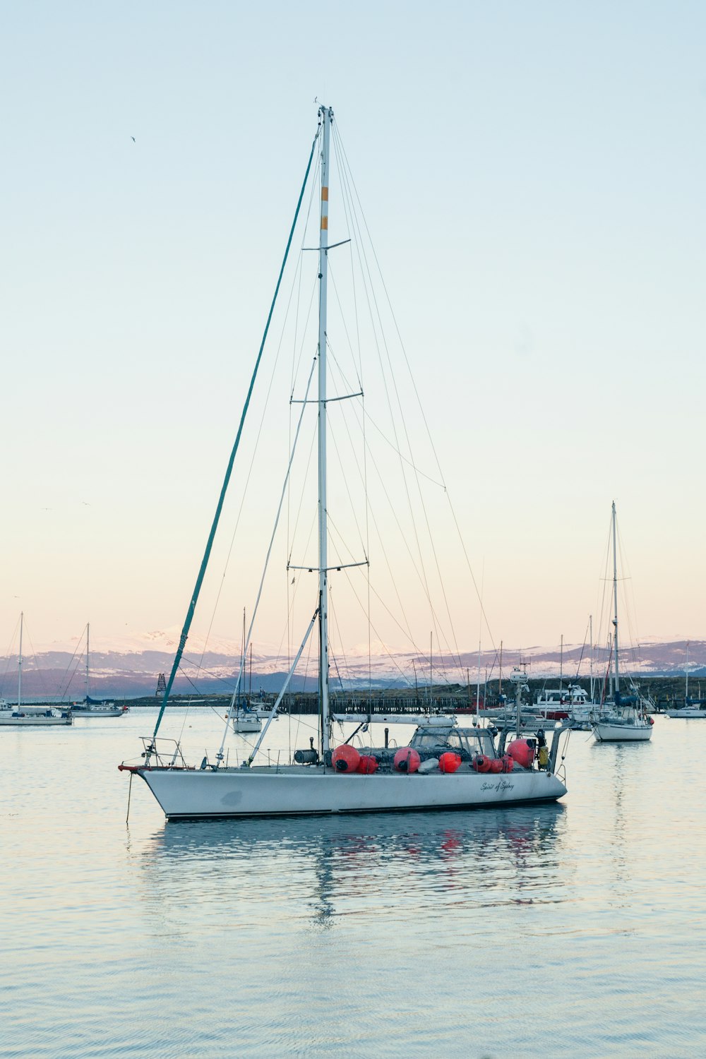 a sailboat in the water with other boats in the background