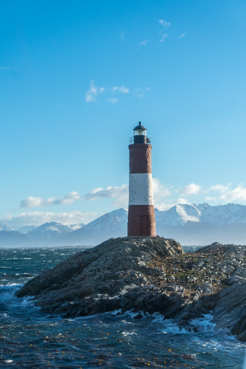 a red and white lighthouse sitting on top of a rock