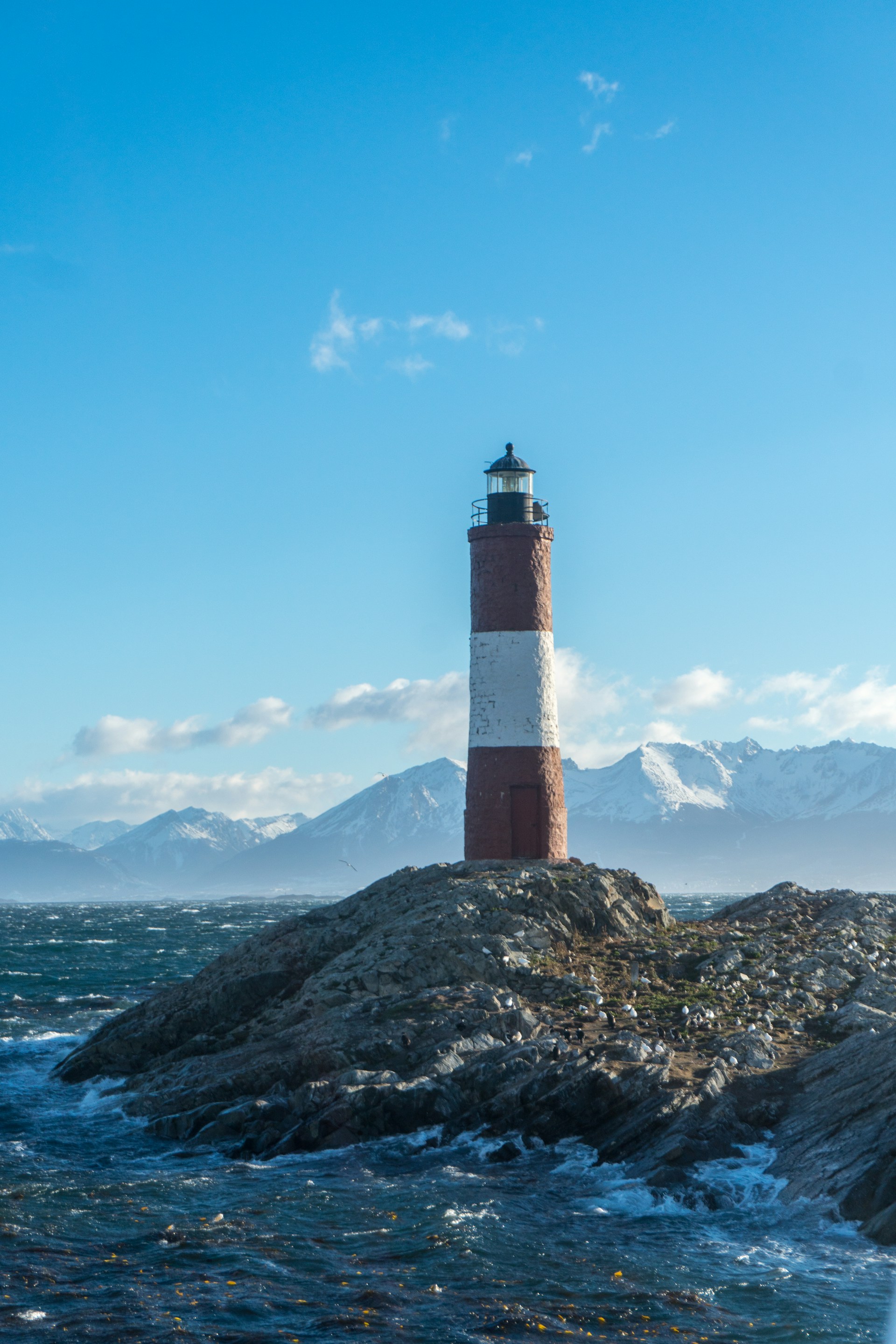 a red and white lighthouse sitting on top of a rock