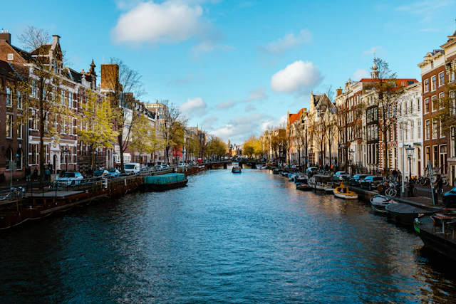 Amsterdam canal lined with historic gabled houses under a blue sky