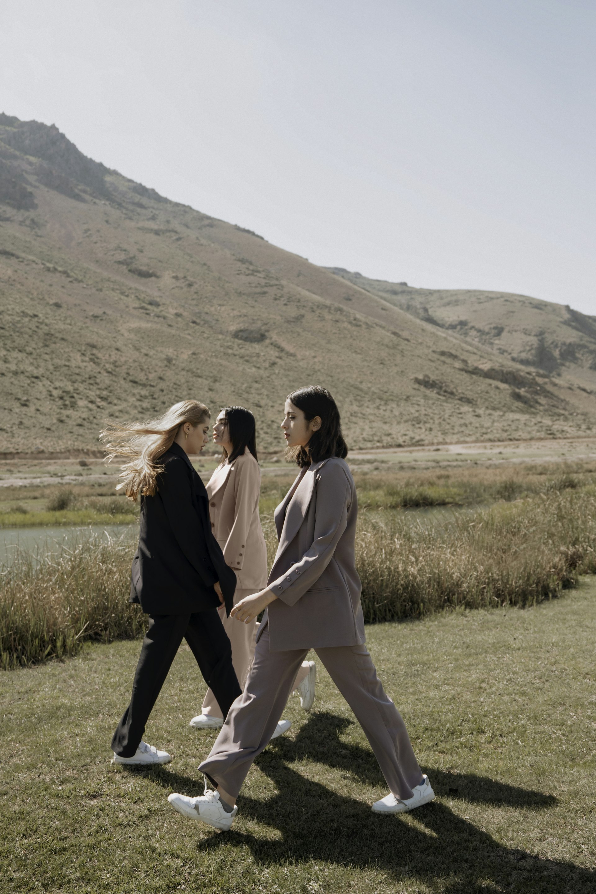 Three people standing close together in a windswept open field.