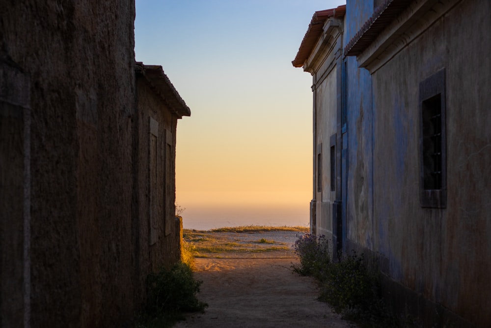 an alley way between two buildings with a view of the ocean