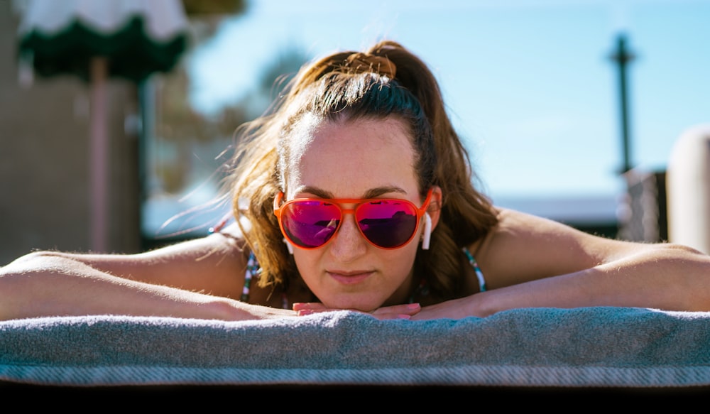 a woman wearing sunglasses laying on a towel