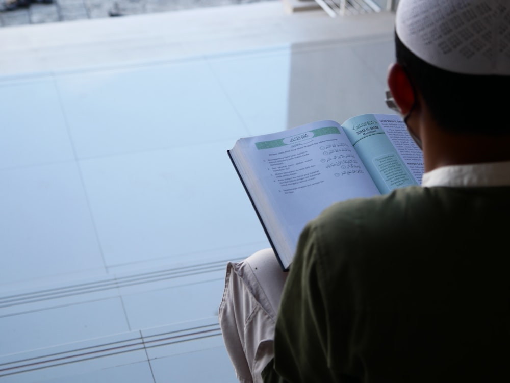 a man reading a book while sitting on a bench