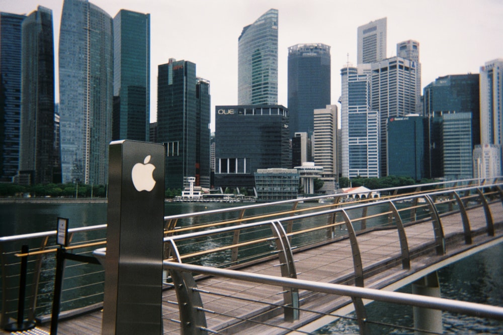 Un letrero de manzana en un puente frente a una ciudad