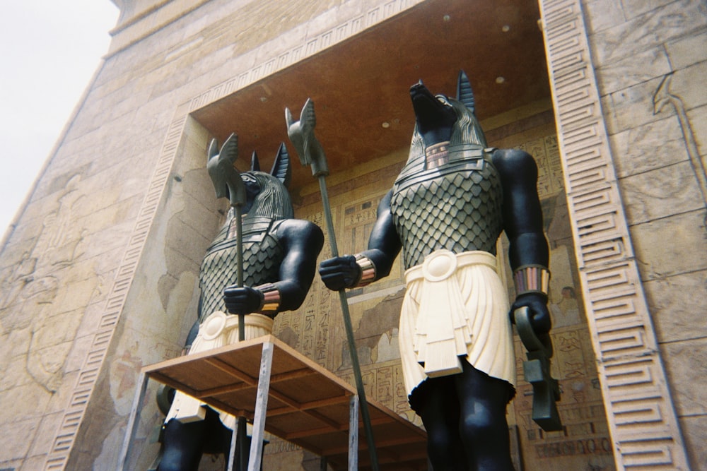 a couple of statues of egyptian gods in front of a building