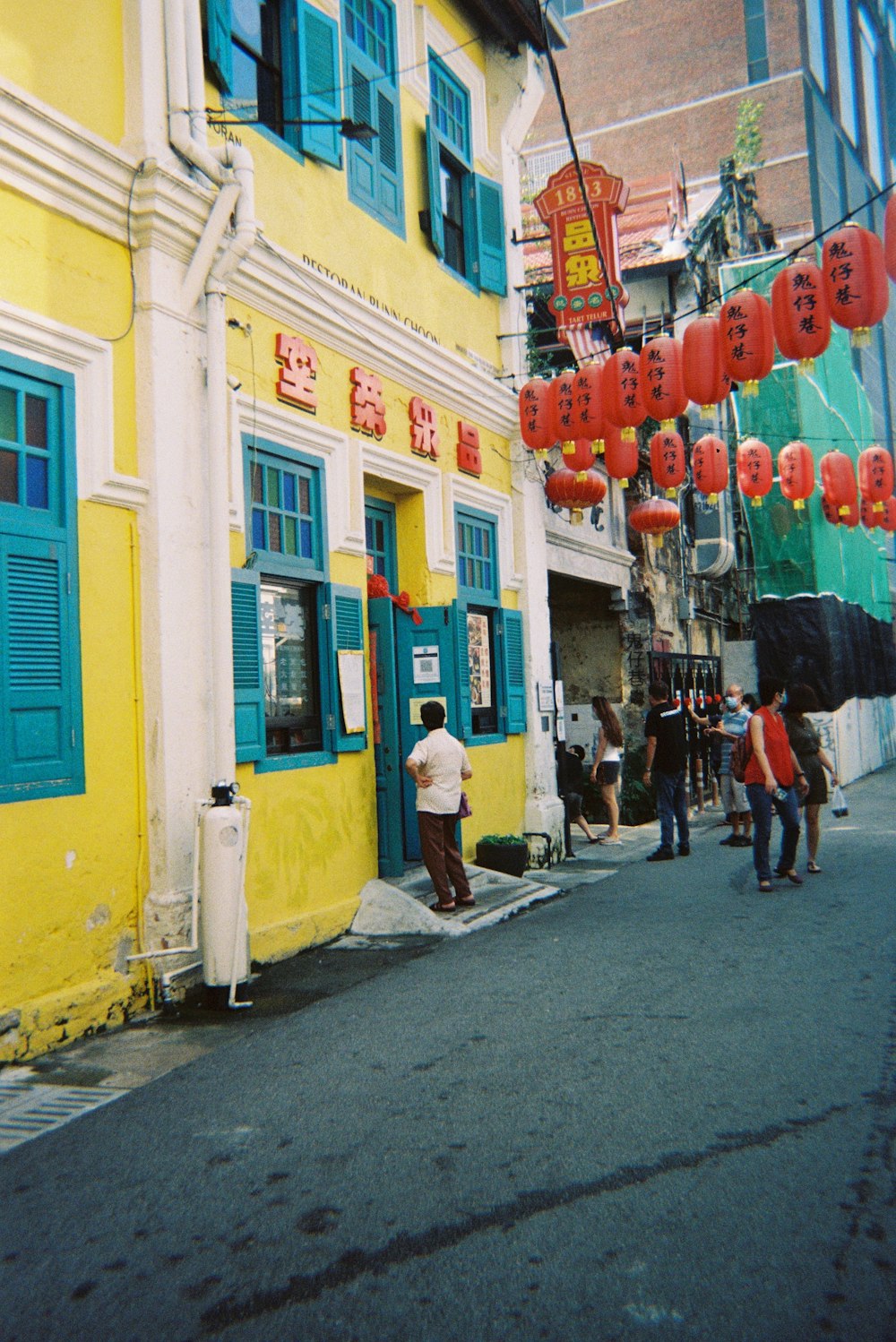 a group of people standing outside of a yellow building