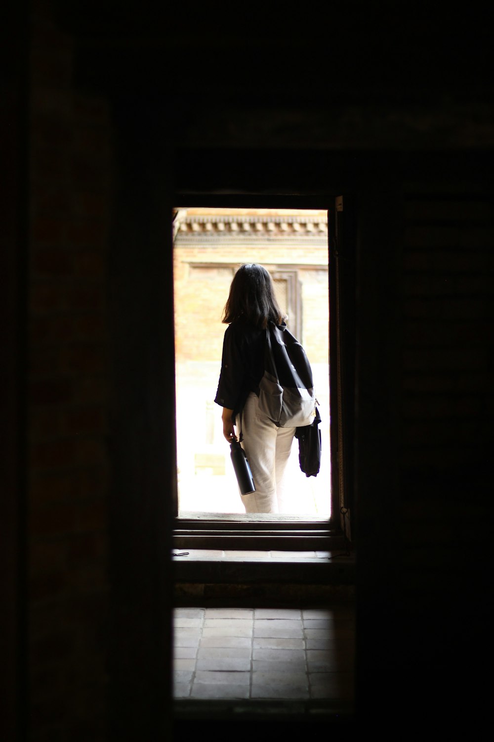 a woman standing in a doorway with a backpack