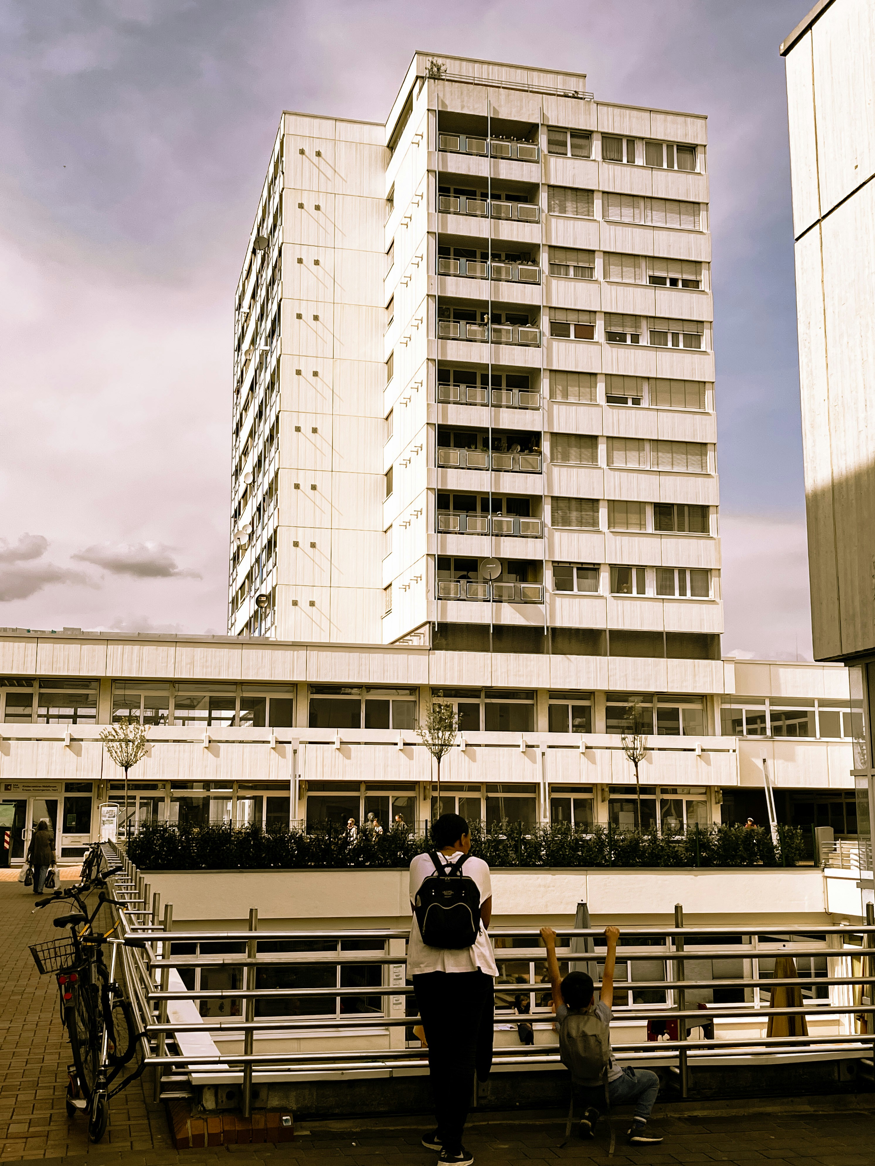 a couple of people standing on a bridge next to a tall building