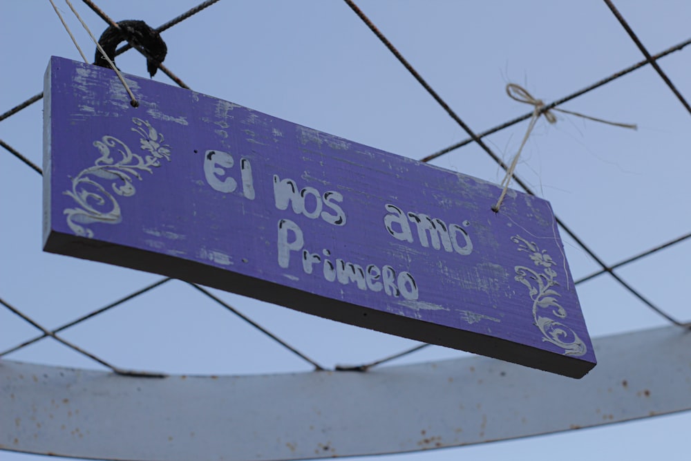 a purple sign hanging from a wire fence