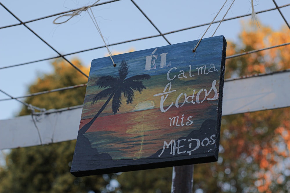 a sign hanging from a power line with a palm tree in the background