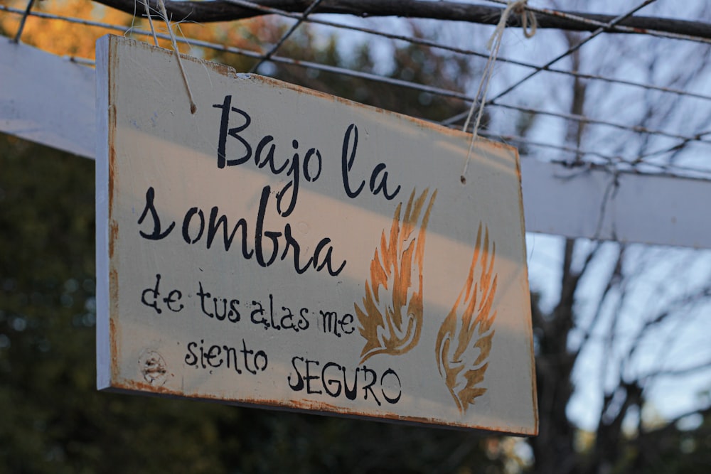 a sign hanging from a power line with a tree in the background