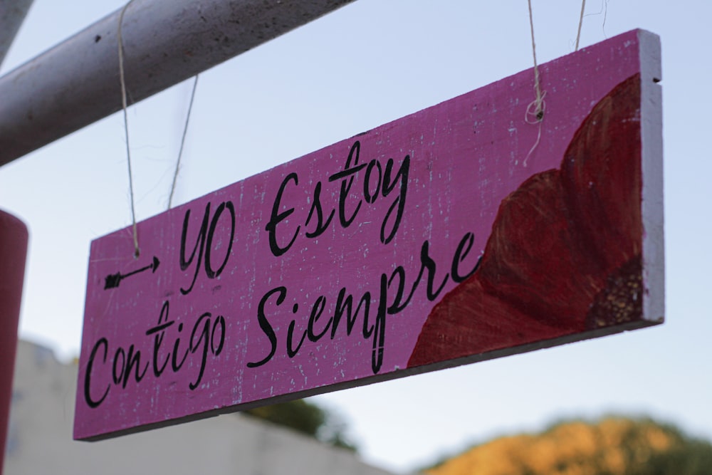 a pink sign hanging from a metal pole