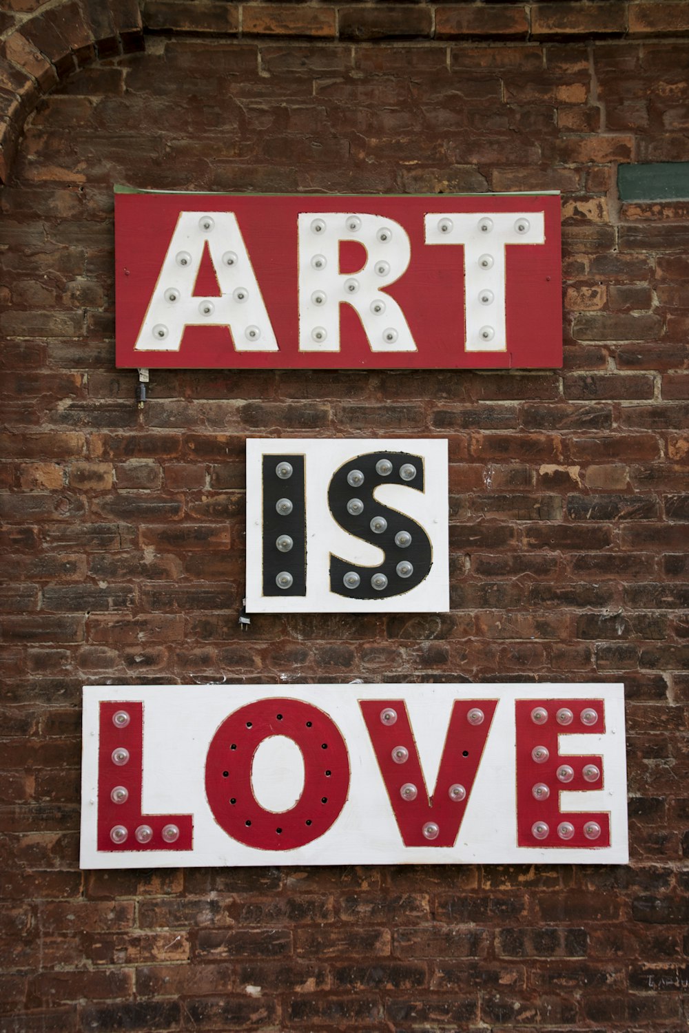 Ein Schild, das besagt, dass Kunst Liebe auf einer Ziegelmauer ist