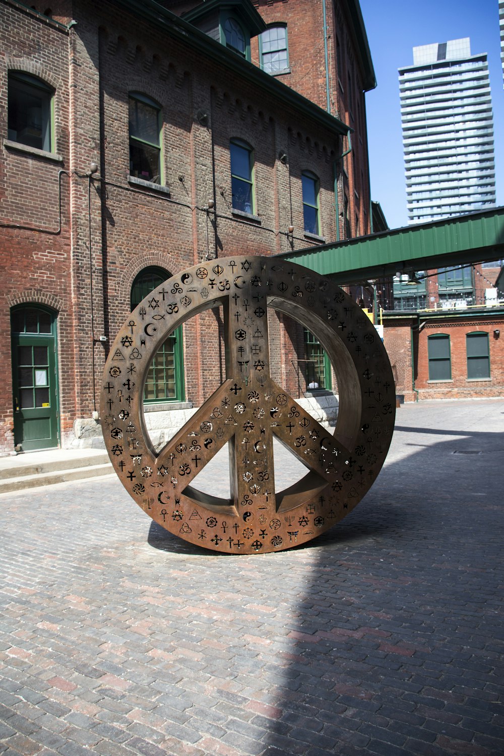 a metal peace sign sitting on top of a brick sidewalk