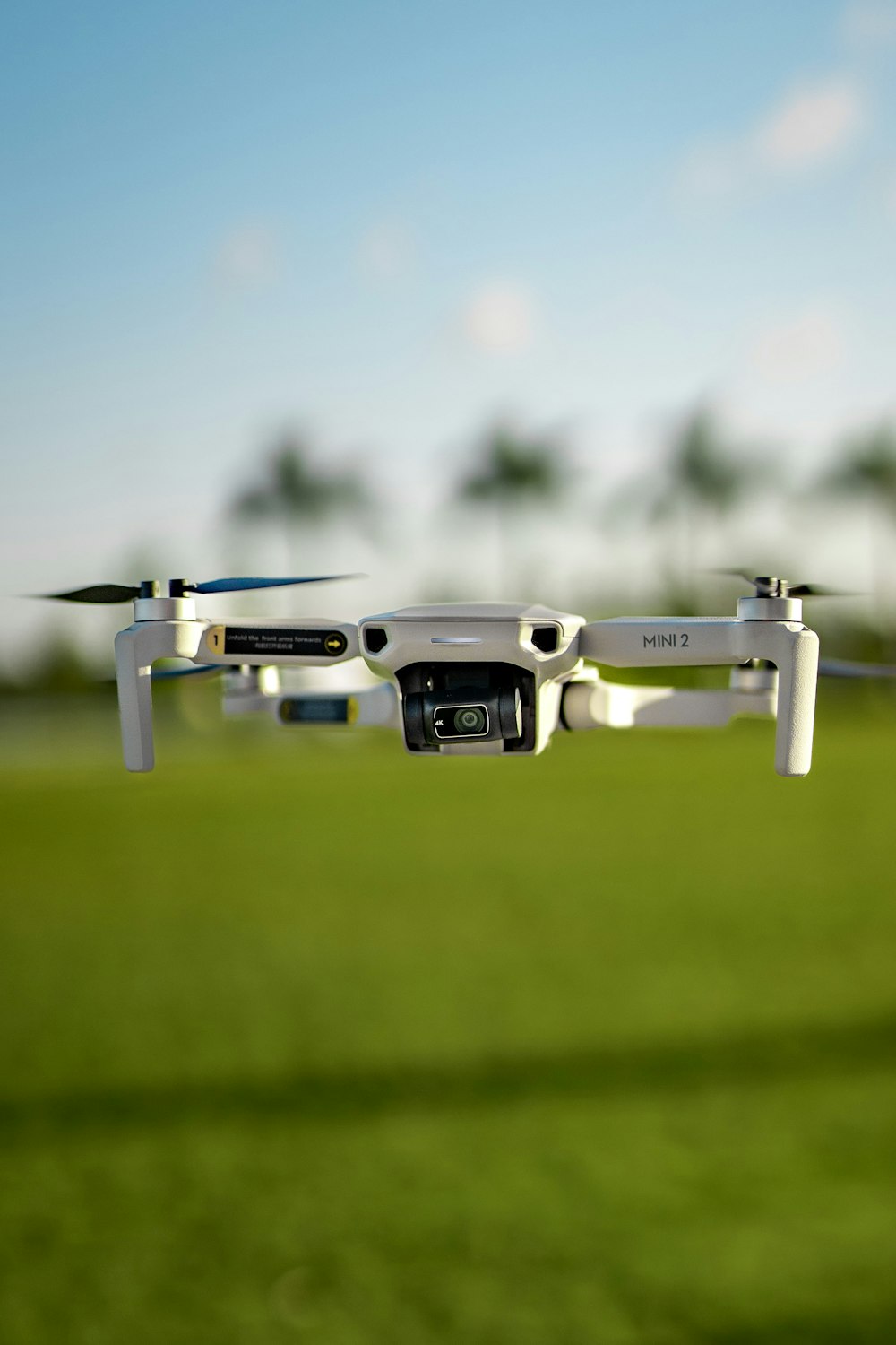 a white and black remote control flying over a green field