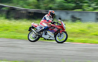 Action shot of a racer wearing Hyper Flow Racing gear speeding on a track, blurred background emphasizing motion.