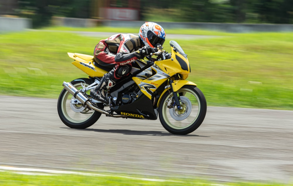 a man riding a yellow motorcycle down a curvy road