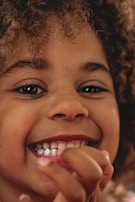 A close-up portrait of a child with bright eyes and a joyful smile.