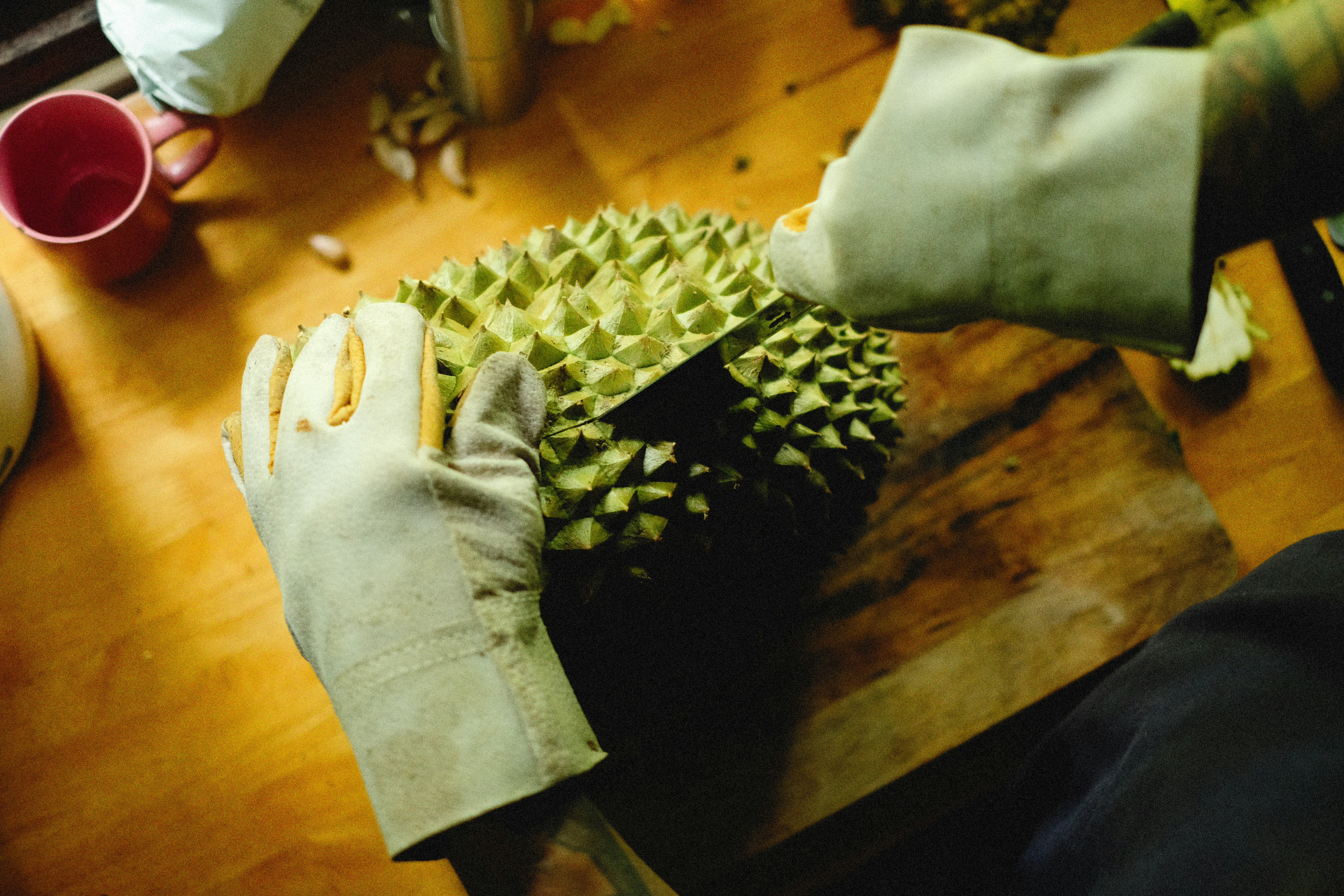 a person holding a piece of fruit on top of a wooden table