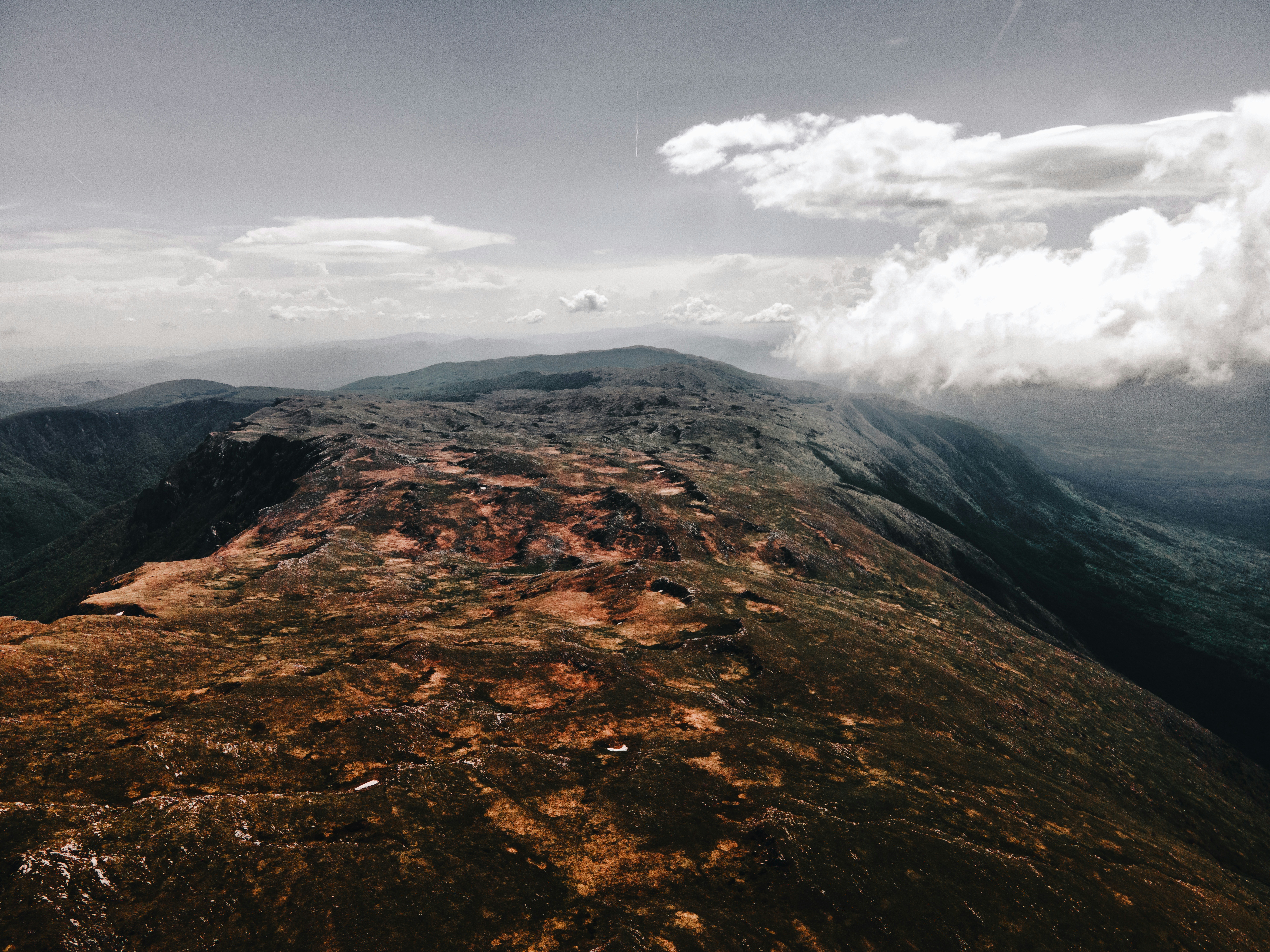 Dramatic landscape aerial shot with deep shadows and atmospheric mist, cinematic wide-angle composition