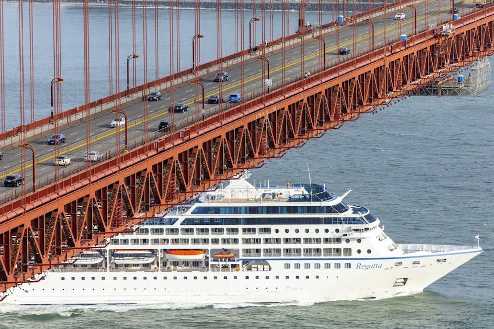 a large cruise ship passing under a bridge