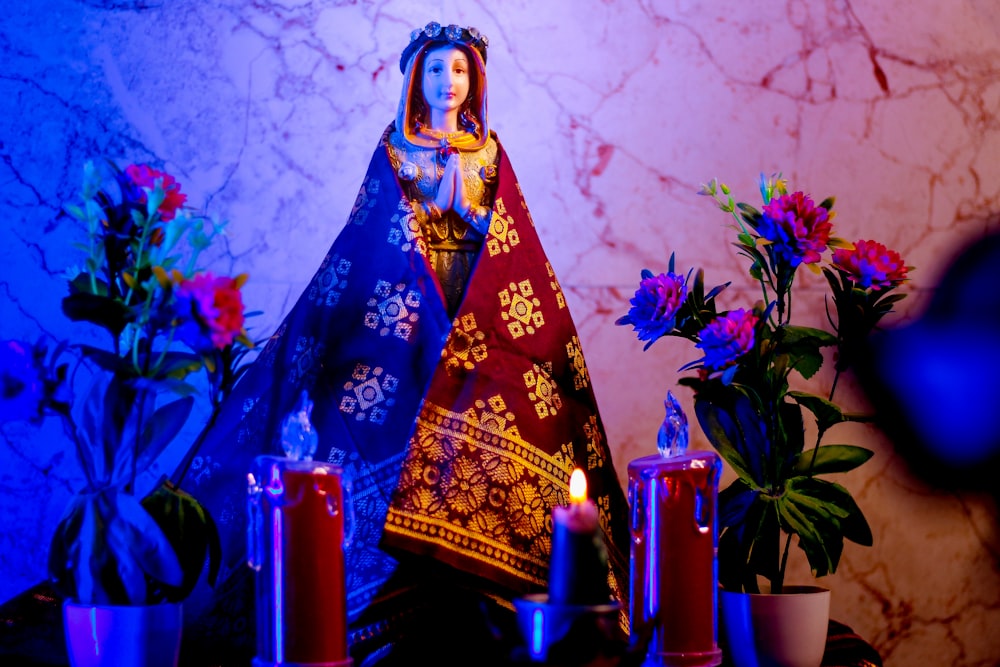 a statue of virgin mary surrounded by flowers and candles