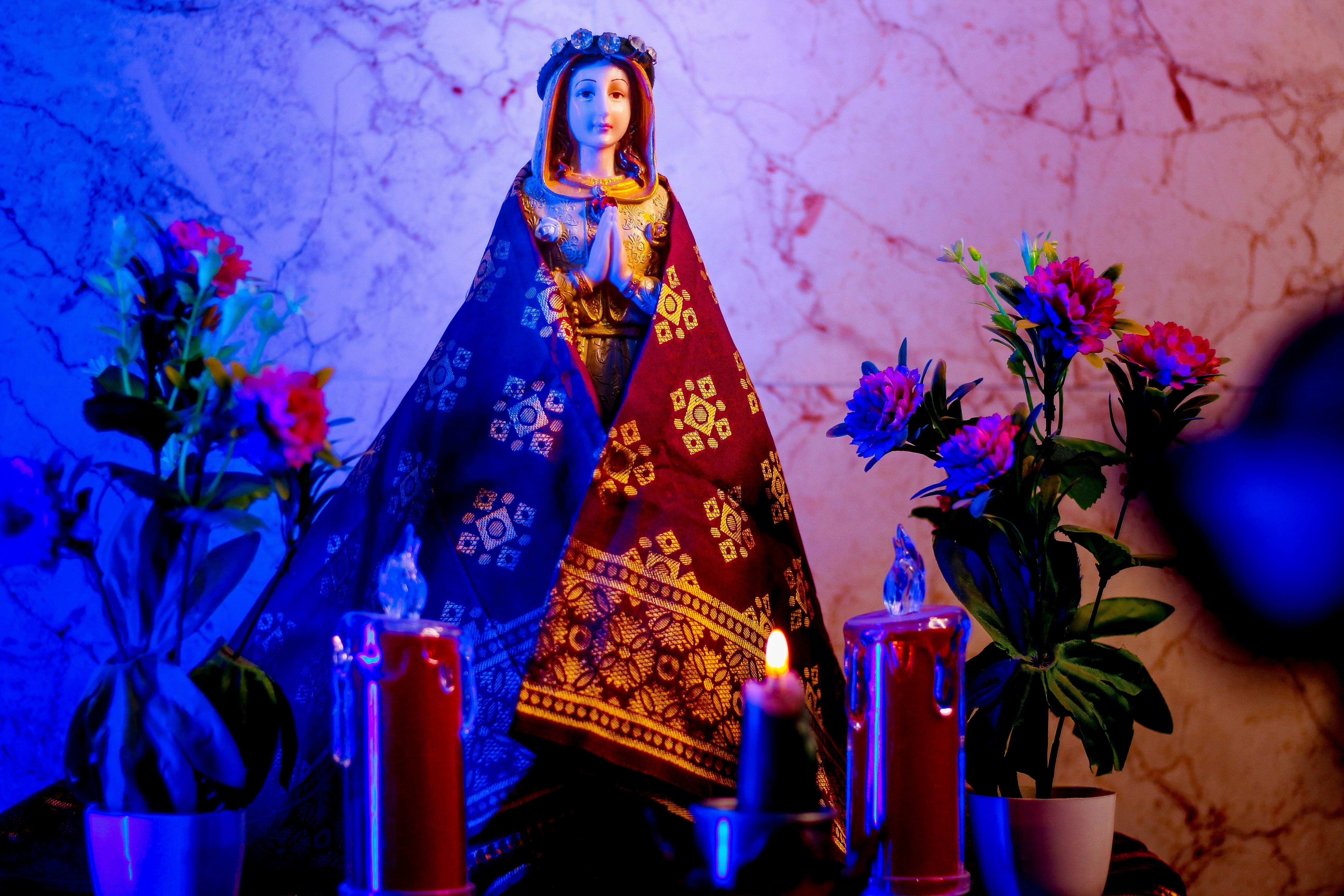 a statue of virgin mary surrounded by flowers and candles